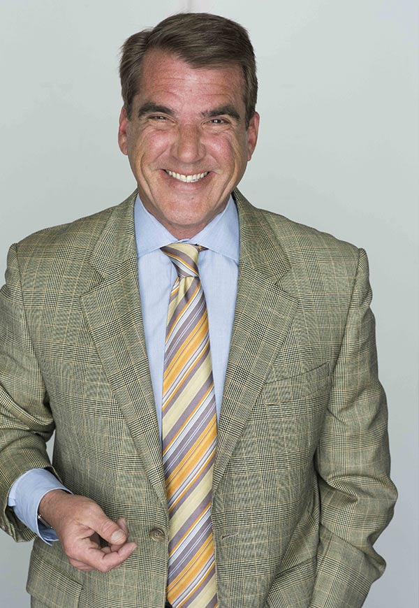 Contact - A man wearing a suit and tie smiling at the camera - Business